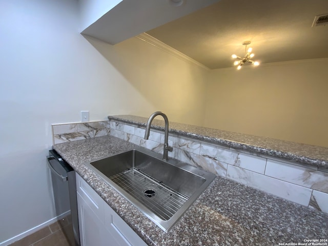 kitchen featuring stone counters, dark tile patterned floors, white cabinets, ornamental molding, and sink