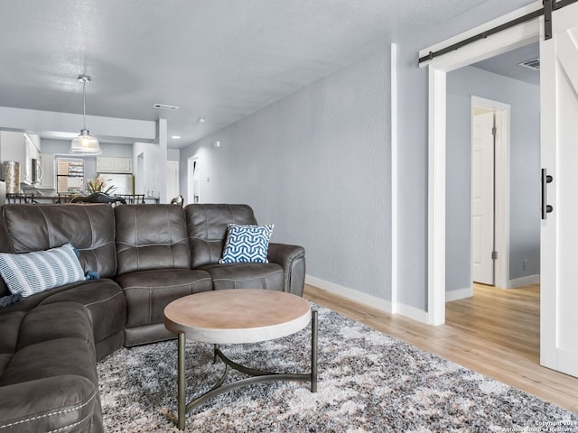 living room with a barn door and light hardwood / wood-style flooring