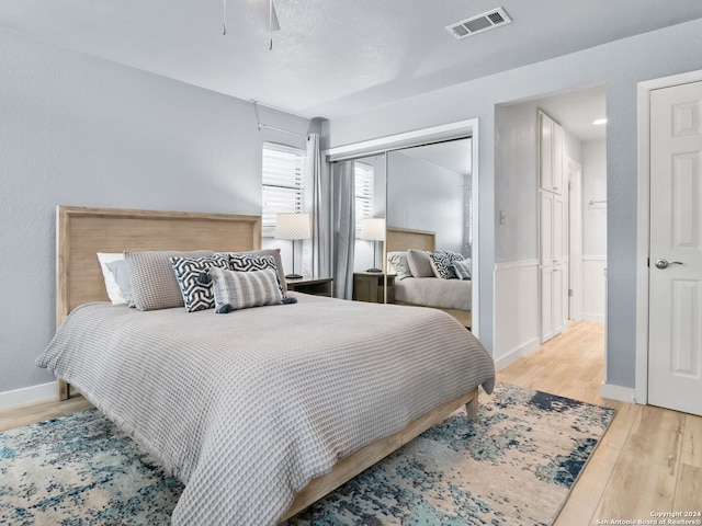 bedroom with light hardwood / wood-style floors, a closet, and ceiling fan