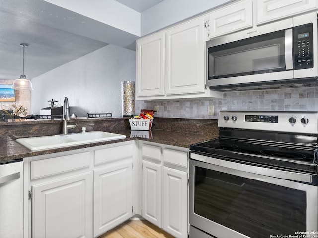 kitchen with sink, white cabinetry, decorative light fixtures, appliances with stainless steel finishes, and light hardwood / wood-style floors