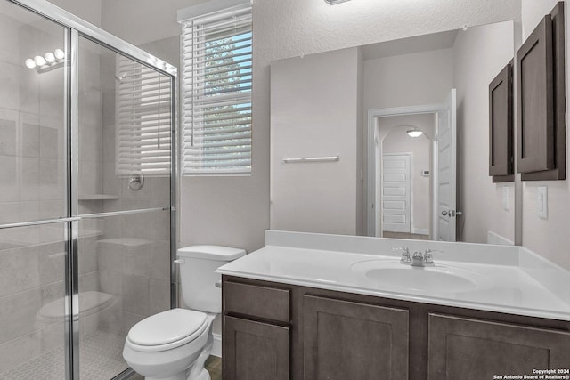 bathroom featuring a shower with shower door, vanity, and toilet