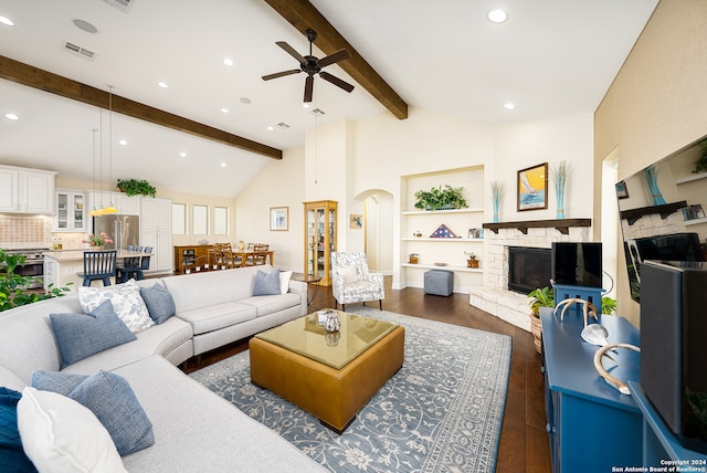 living room featuring dark wood-type flooring, vaulted ceiling with beams, ceiling fan, built in features, and a fireplace