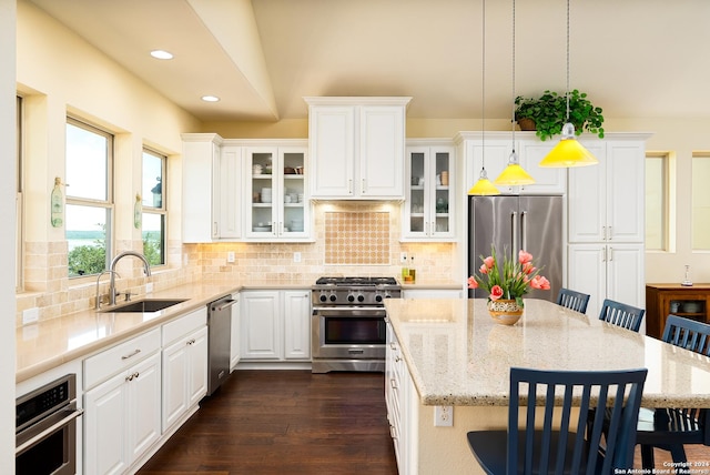 kitchen featuring backsplash, stainless steel appliances, decorative light fixtures, a water view, and a center island