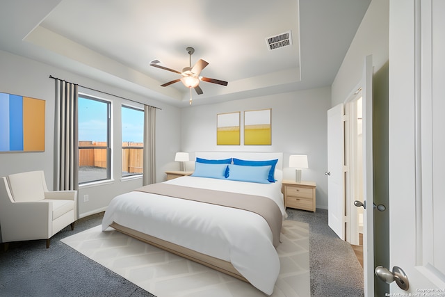 carpeted bedroom featuring a raised ceiling and ceiling fan