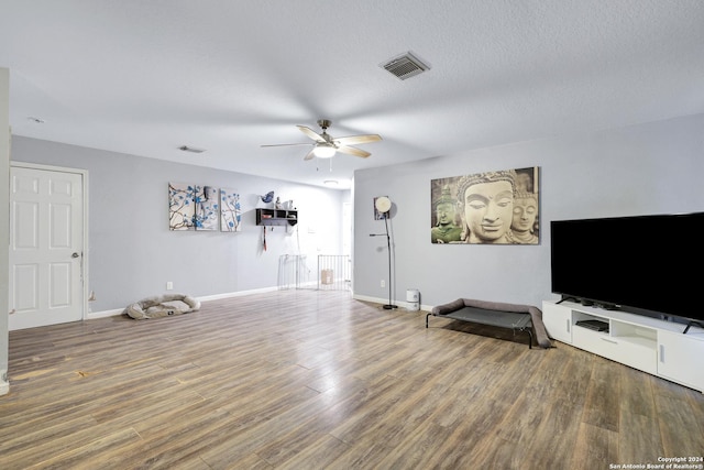 unfurnished living room featuring ceiling fan, wood-type flooring, and a textured ceiling