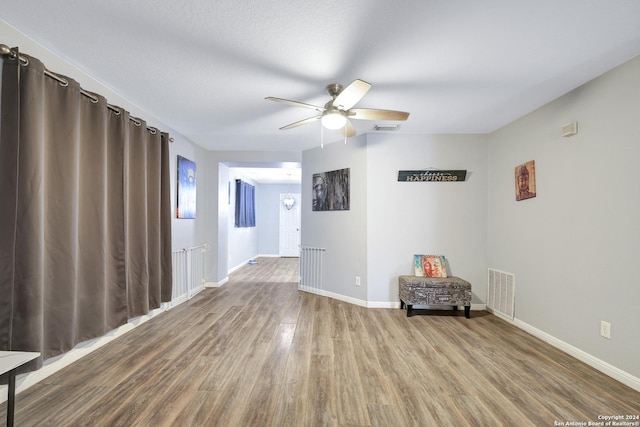 empty room with ceiling fan, wood-type flooring, and a textured ceiling