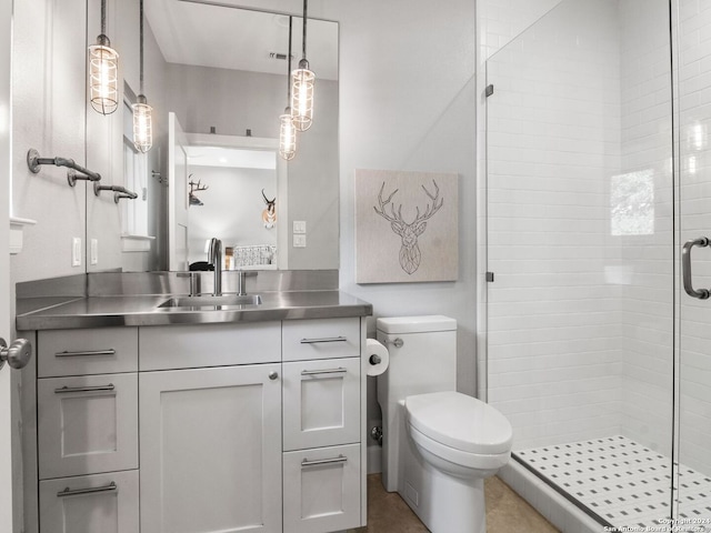 bathroom with a shower with shower door, vanity, tile patterned floors, and toilet