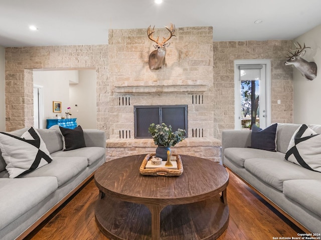 living room featuring a stone fireplace and dark hardwood / wood-style flooring