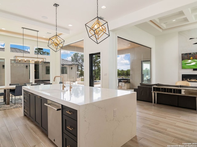 kitchen featuring decorative light fixtures, beam ceiling, sink, light wood-type flooring, and light stone countertops