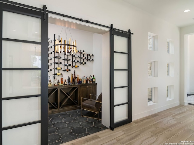 wine cellar with a barn door and hardwood / wood-style flooring