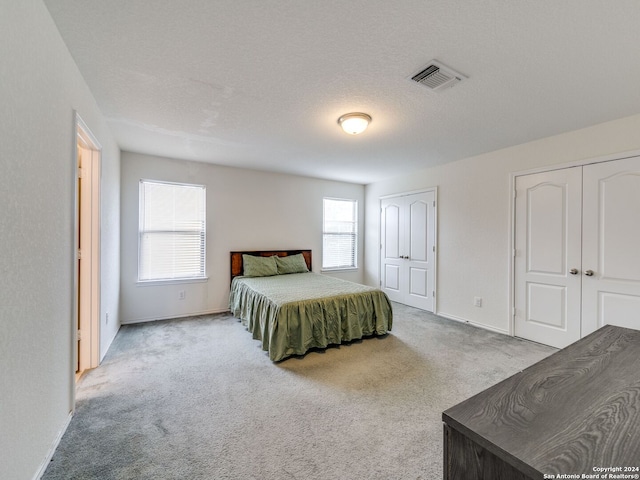 bedroom with multiple closets, carpet flooring, and a textured ceiling