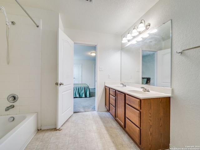 bathroom with vanity, a textured ceiling, and tiled shower / bath