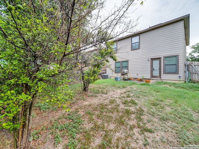 rear view of property featuring central AC and a lawn