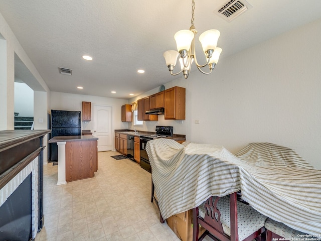 kitchen featuring pendant lighting, sink, black appliances, a kitchen island, and a chandelier