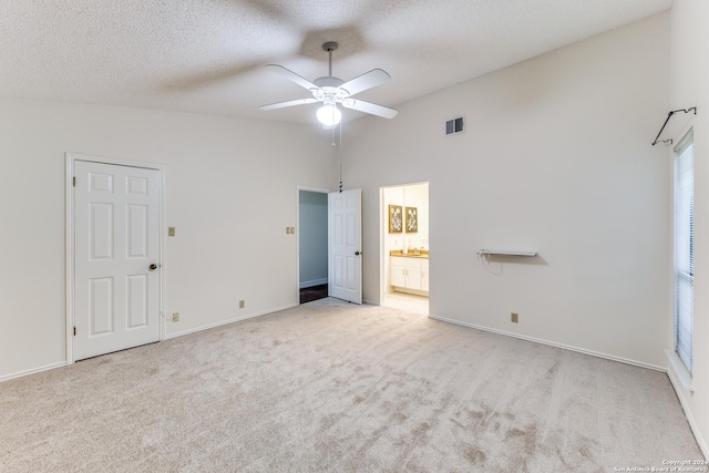 unfurnished bedroom featuring light colored carpet, ceiling fan, a textured ceiling, and connected bathroom