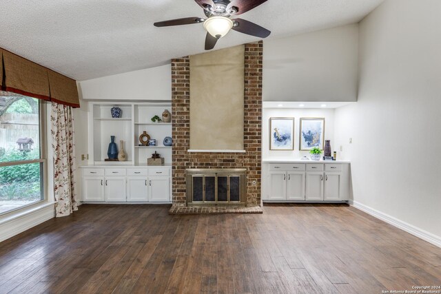 unfurnished living room with lofted ceiling, a brick fireplace, a textured ceiling, and a wealth of natural light