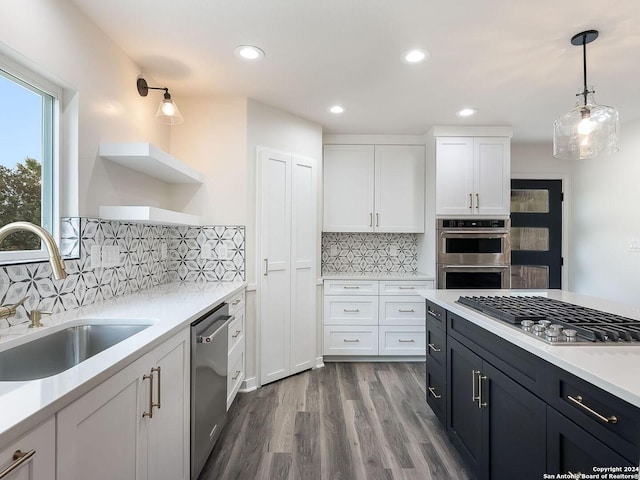 kitchen with white cabinets, stainless steel appliances, decorative light fixtures, and sink