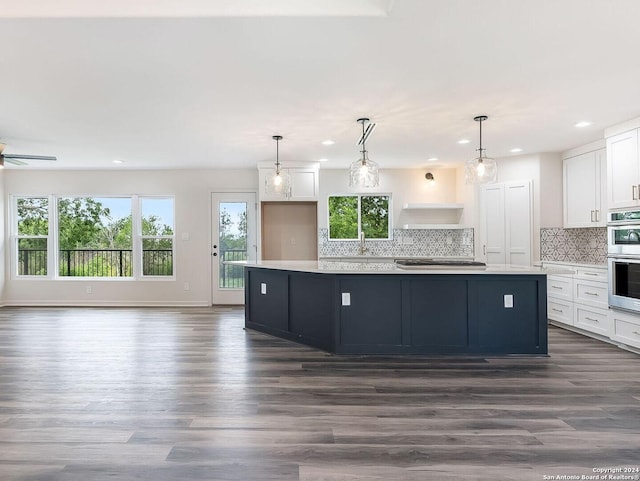 kitchen featuring white cabinetry, hanging light fixtures, a kitchen island, dark wood-type flooring, and double oven