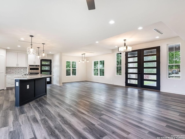 unfurnished living room with french doors, an inviting chandelier, and dark wood-type flooring