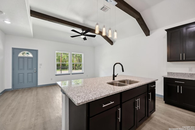 kitchen featuring a kitchen island with sink, sink, beam ceiling, and light hardwood / wood-style flooring