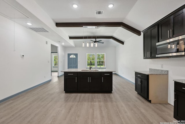 kitchen featuring sink, vaulted ceiling with beams, light hardwood / wood-style flooring, ceiling fan, and light stone countertops