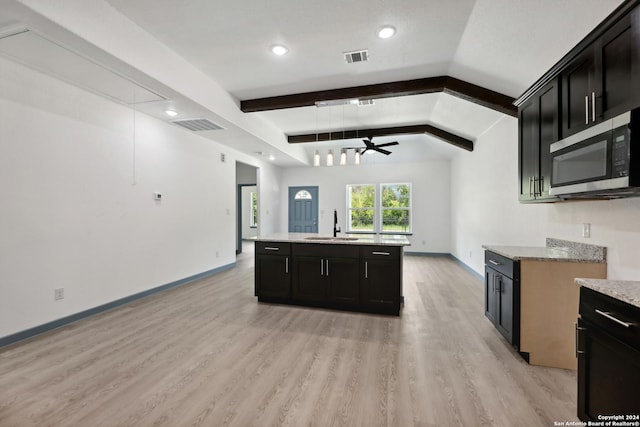 kitchen featuring sink, light hardwood / wood-style flooring, ceiling fan, a kitchen island with sink, and vaulted ceiling with beams