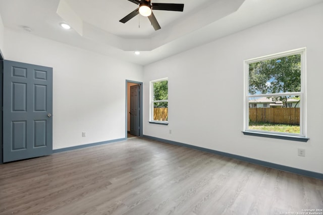 spare room featuring ceiling fan, a raised ceiling, and light wood-type flooring