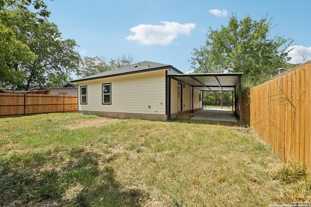 back of property with a carport and a yard