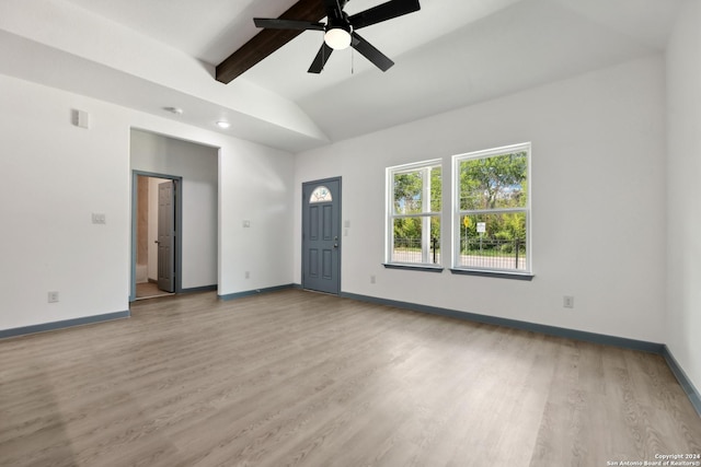 empty room featuring ceiling fan, lofted ceiling with beams, and light hardwood / wood-style flooring