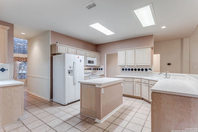 kitchen with kitchen peninsula, backsplash, sink, a center island, and white appliances