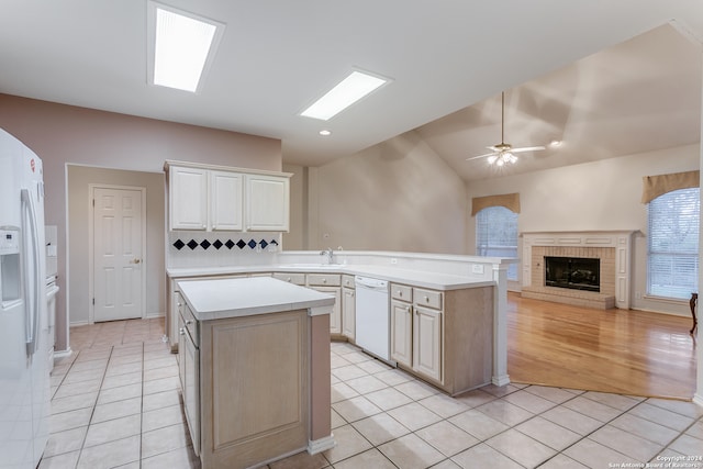 kitchen featuring lofted ceiling, a kitchen island, a fireplace, white appliances, and ceiling fan