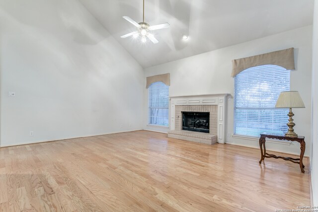 unfurnished living room featuring light hardwood / wood-style flooring, high vaulted ceiling, a fireplace, and ceiling fan