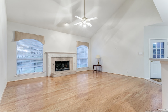 unfurnished living room with ceiling fan, high vaulted ceiling, light wood-type flooring, and a brick fireplace