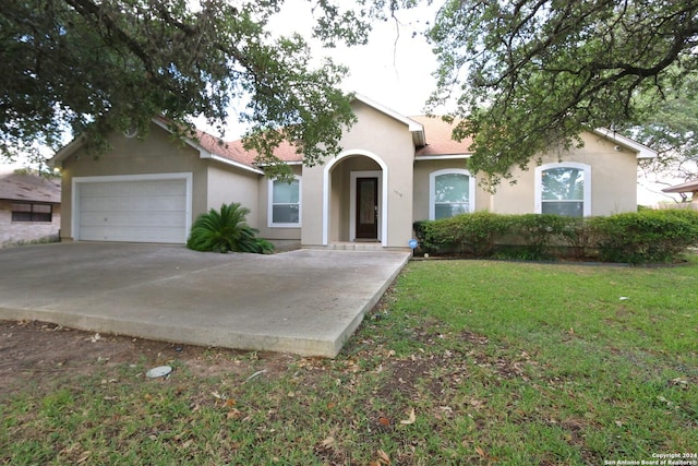 view of front of property with stucco siding, an attached garage, driveway, and a front yard