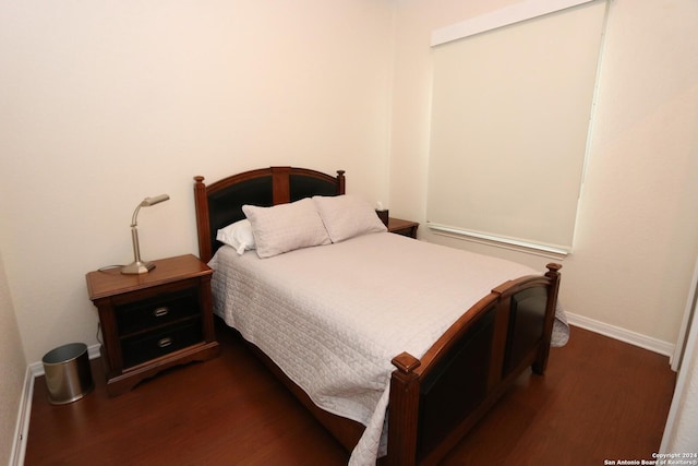 bedroom with dark wood-type flooring and baseboards