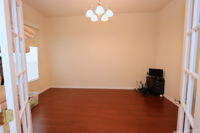 unfurnished room featuring a chandelier, dark hardwood / wood-style floors, and french doors