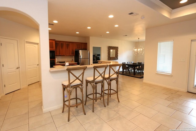 kitchen with freestanding refrigerator, recessed lighting, a peninsula, a breakfast bar area, and light countertops