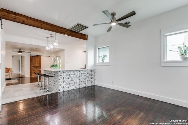 interior space with beam ceiling, a barn door, and light hardwood / wood-style floors