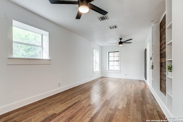 spare room featuring ceiling fan, built in features, and hardwood / wood-style flooring