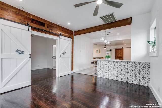 spare room featuring ceiling fan, dark hardwood / wood-style flooring, and a barn door