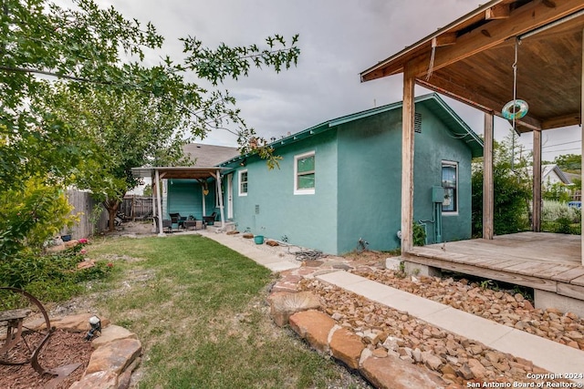 rear view of house featuring a wooden deck and a lawn