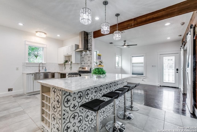 kitchen with a barn door, stainless steel stove, white cabinets, a breakfast bar, and sink