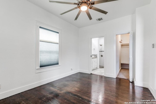 unfurnished bedroom featuring ensuite bath, a walk in closet, dark hardwood / wood-style flooring, a closet, and ceiling fan