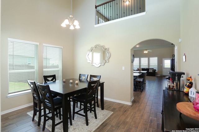 dining space with a wealth of natural light, a towering ceiling, and dark wood-type flooring