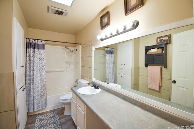 full bathroom with hardwood / wood-style flooring, vanity, shower / bathtub combination with curtain, and toilet