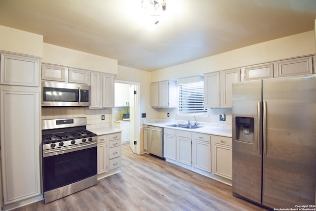 kitchen with sink, backsplash, light hardwood / wood-style flooring, and stainless steel appliances