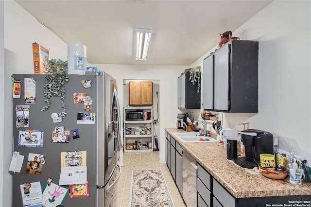 kitchen with sink, black microwave, stainless steel fridge, and light tile patterned floors