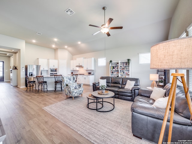 living room with plenty of natural light, ceiling fan, lofted ceiling, and light hardwood / wood-style floors