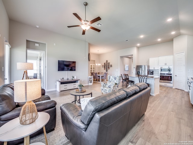 living room with ceiling fan, light hardwood / wood-style flooring, and vaulted ceiling