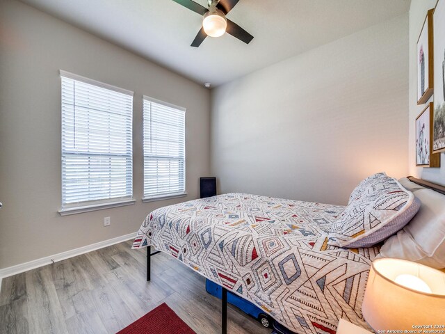 bedroom with multiple windows, ceiling fan, and wood-type flooring